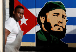 An employee of a state-owned candy store looks outside near a painting depicting Cuba's former President Fidel Castro, following the announcement of Castro's death, in Havana, Nov. 27. Castro, who seized power in a 1959 revolution and governed Cuba until 2006, died Nov. 25 at the age of 90. (CNS photo/Reuters) See CASTRO-DEATH-POPE-WENSKI Nov. 27, 2016.