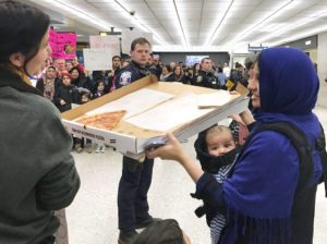 A woman offers pizza to people protesting the travel ban imposed by President Donald Trump at Washington Dulles International Airport in Dulles, Va., Jan. 28.(CNS photo/Yeganeh Torbati, Reuters) See TRUMP-BAN-US-REACTION Jan. 30, 2017.