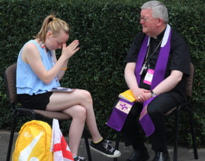 A World Youth Day pilgrim becomes emotional as a priest hears her confession in 2016 at Sacred  Heart Church in Krakow, Poland. As the Catholic Church prepares for a meeting of the Synod of Bishops focused on youth, the pope wrote a letter to young people saying the church wants "to listen to your voice, your sensitivities and your faith, even your doubts and your criticism." (CNS photo/Bob Roller) See POPE-SYNOD-YOUTH Jan. 13, 2017.