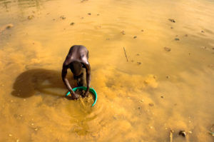 A Congolese mine worker rinses gold-rich earth out of the pit for water processing in 2009 in Chudja. Church leaders say telling companies they no longer had to disclose whether their firms use "conflict minerals" would be a bad move. (CNS photo/Marc Hofer, EPA) See CONFLICT-MINERALS-POTENTIAL-ORDER Feb. 17, 2017.