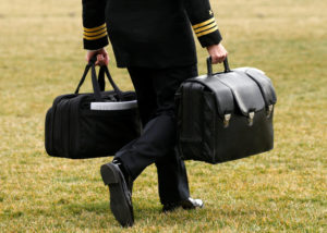 A military aide, carrying the "football" containing launch codes for nuclear weapons, accompanies U.S. President Donald Trump onto Marine One upon Trump's departure from the White House. The chairman of a U.S. bishops' committee urged Secretary of State Rex Tillerson to pursue additional reductions in the nuclear arsenals of the United States and Russia. (CNS photo/Kevin Lamarque, Reuters) See CANTU-NUCLEAR-WEAPONS-CUTS Feb. 15, 2017.