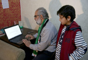 Abdul Hakim Kiwan, a Syrian refugee from Daraa, and his son, Ibrahim, are seen working at a computer Jan. 30 at their temporary home in Amman, Jordan. Kiwan and his family are part of a U.S. refugee resettlement program that President Donald Trump has suspended  for 120 days. (CNS photo/Jamal Nasrallah, EPA) See WASHINGTON-LETTER-REFUGEES-LEGAL Feb. 3, 2017.
