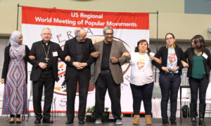 Los Angeles Archbishop Jose H. Gomez, second from left, links arms with other participants on stage after a panel discussion on migration issues Feb. 17 during the U.S. Regional World Meeting of Popular Movements in Modesto, Calif. The archbishop said fear has spread among unauthorized immigrants in the U.S. as the government cracks down on illegal immigration. (CNS photo/Dennis Sadowski) See WMPM-SANCTUARY Feb. 22, 2017.
