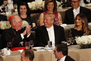 Donald Trump, then the Republicans' nominee for U.S. president, smiles as he sits between New York Cardinal Timothy M. Dolan and wife Melania during the 71st annual Alfred E. Smith Memorial Foundation Dinner in New York City Oct. 20. Cardinal Dolan is among religious leaders will read from Scripture at Trump's presidential inauguration Jan. 20. (CNS photo/Gregory A. Shemitz) See  INAUGURATION-TRUMP-DOLAN Dec. 28, 2016.