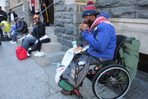 Able Putu, a homeless man in a wheelchair, eats a meal on a Washington street March 8 prepared by volunteers of the St. Maria's meals program run by Catholic Charities. (CNS photo/Chaz Muth) See LENT-HELP-HOMELESS March 16, 2017.