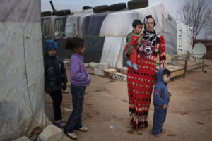 A mother stands with her children in 2014 in an informal tented settlement near Deir el Ahmar in the northern Bekaa Valley, Lebanon. (CNS photo/Sam Tarling, CRS) See REFUGEES-MAHONY-TOMASI March 9, 2017