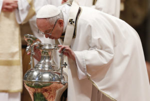 Pope Francis breathes over chrism oil, a gesture symbolizing the infusion of the Holy Spirit, during the Holy Thursday chrism Mass in St. Peter's Basilica at the Vatican April 13. (CNS photo/Paul Haring) See POPE-HOLYTHURSDAY-CHRISM April 13, 2017.