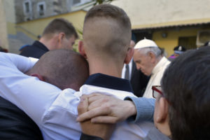 Inmates embrace as Pope Francis prays April 13 at Paliano prison outside of Rome. The pontiff celebrated Holy Thursday Mass of the Lord's Supper and washed the feet of 12 inmates at the maximum security prison. (CNS photo/L'Osservatore Romano) See See POPE-HOLY-THURSDAY April 13, 2017.