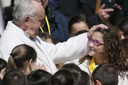 Pope Francis greets a young choir member during his general audience in St. Peter's Square at the Vatican April 19. (CNS photo/Paul Haring) See POPE-AUDIENCE-RESURRECTION April 19, 2017.