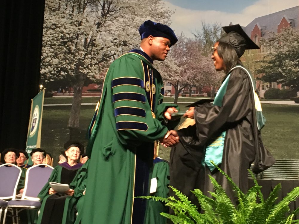 Elms College President Harry E. Dumay presents diplomas to graduates at
