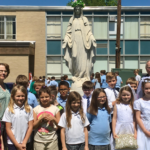 Students from Mater Dolorosa School pose with their teacher and Father Albert Scherer, pastor of Our Lady of the Cross Parish, after the recent May Crowning.