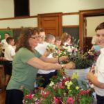 National Junior Honor Society adviser Paula Donais assists St. Joan of Arc School students with their Mother's Day Flower Sale.