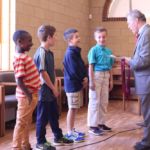 Lad Pfeifer (right), St. Michael's Cathedral organist and music director, presents awards for music theory, leadership, stepping up from one level to the next and other achievements to members of the cathedral's Choir of Boys and Adults at the choir's year-end event.