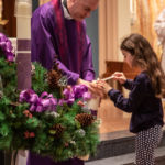 A young parishioner is assisted by Msgr. Christopher Connelly, rector, in lighting the Advent candle at St. Michael's Cathedral in Springfield.