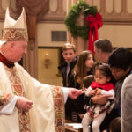 Bishop Rozanski greets a young parishioner during the Christmas Eve Mass at St. Michael's Cathedral in Springfield.